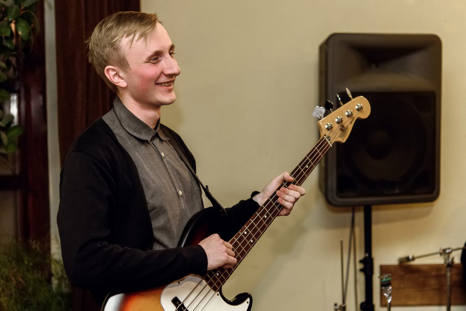 stylish bass guitarist playing on a concert on a background of his band